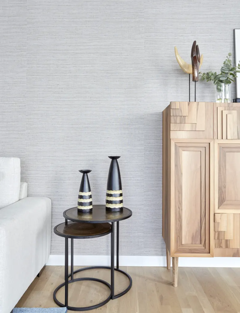 Detalle de mueble de madera y jarrones junto a pared de papel pintado